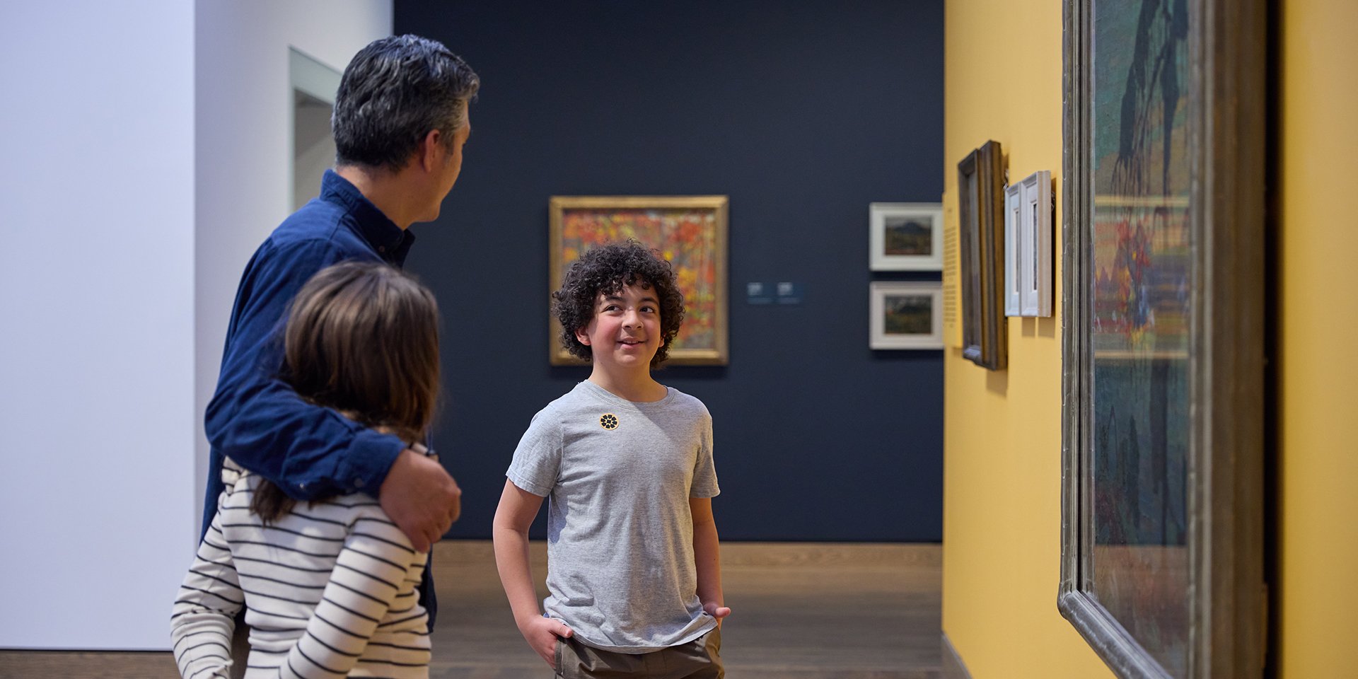 A family standing in front of a painting.