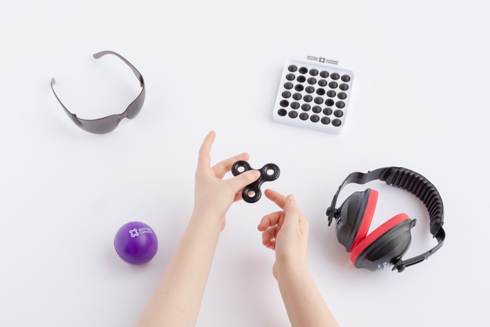 A sensory kit containing dark glasses, noise-reducing earmuffs, and three fidget items.